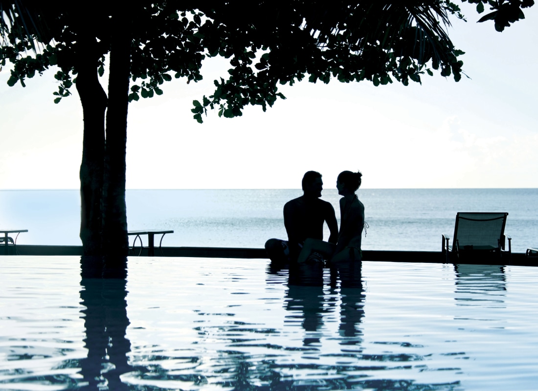 Honeymoon couple relaxing in pool and enjoying the dramatic ocean view
